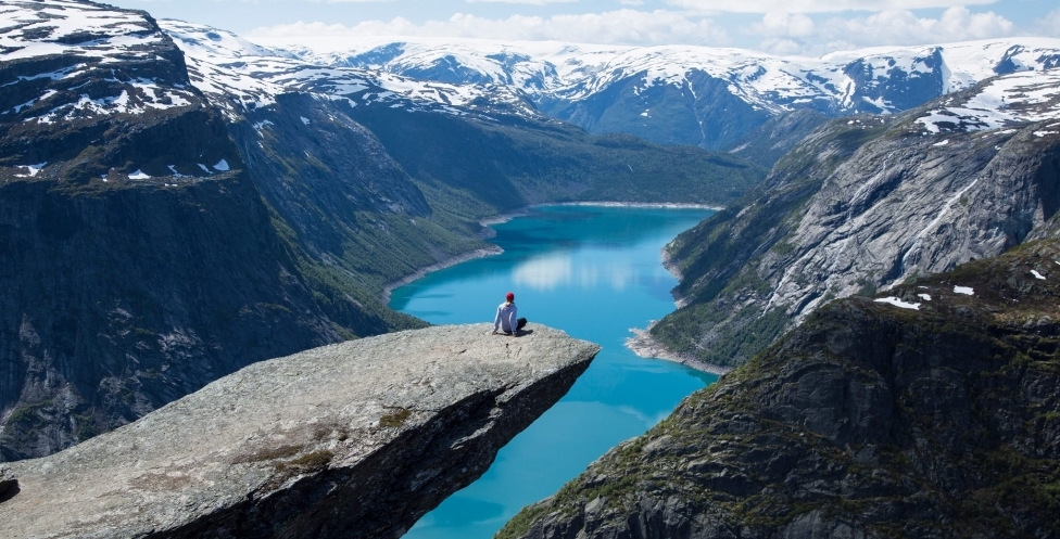 Person sitting on edge above lake